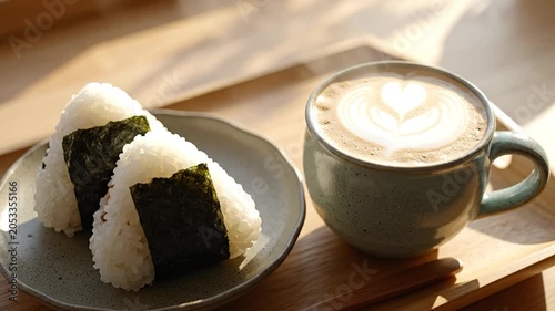 Onigiri rice balls and latte with heart art on a wooden tray in warm morning sunlight
