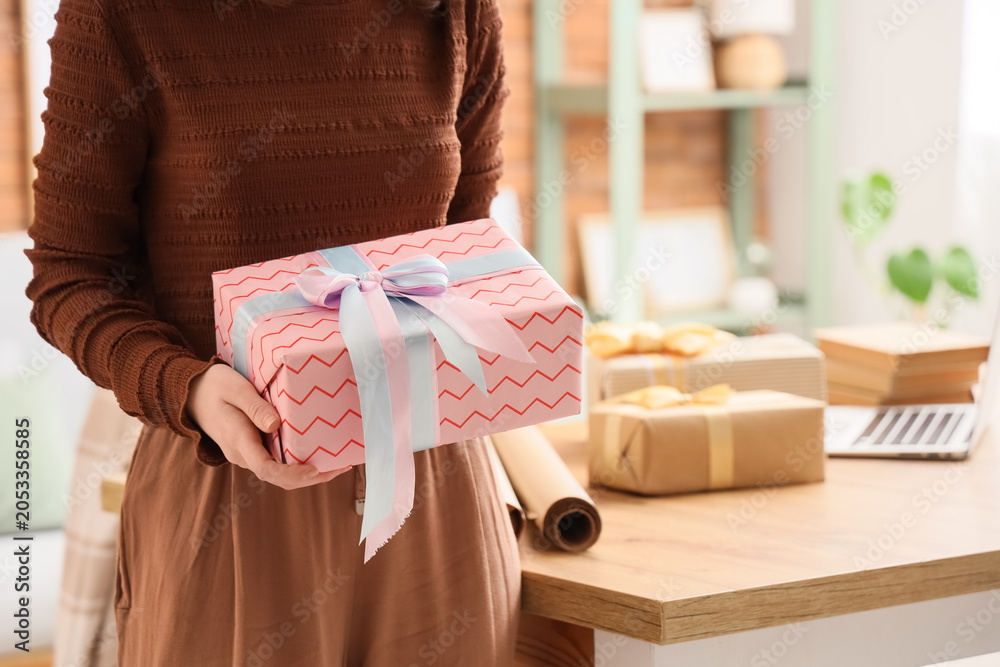 Fototapeta premium Woman holding a beautifully wrapped pink gift box with blue and pink ribbon, celebration and holiday present