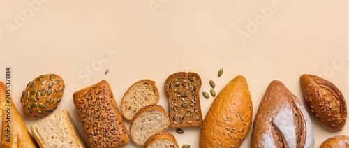 Assorted bread loaves and slices arranged at the bottom with copy space on beige surface banner