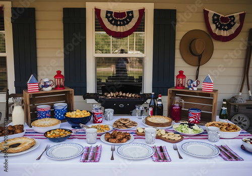 People gather on a house porch for a festive outdoor meal with food