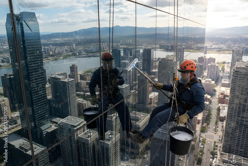 Window washers cleaning skyscraper facade high above city