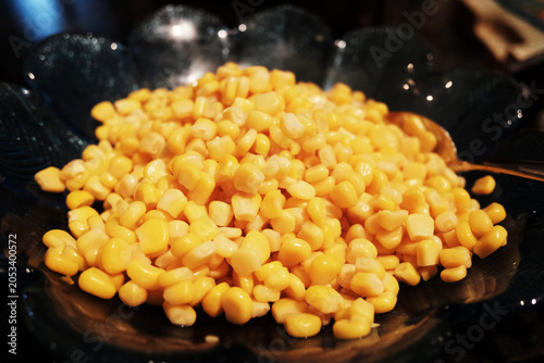 Close up of boiled corn seeds spinning in black dish