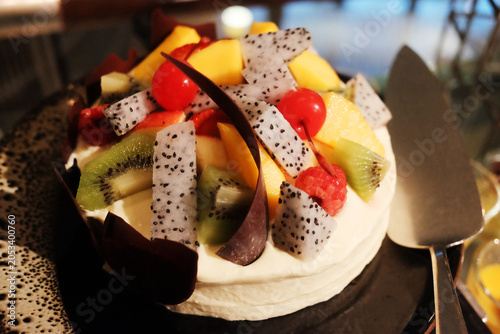Fresh homemade cheese cake with cherry and tropical fruits topping with cream
