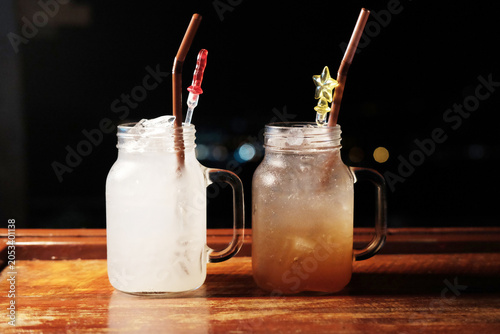 Fresh two glasses of ice Lemonade juice and plum juice on wooden counter in the night