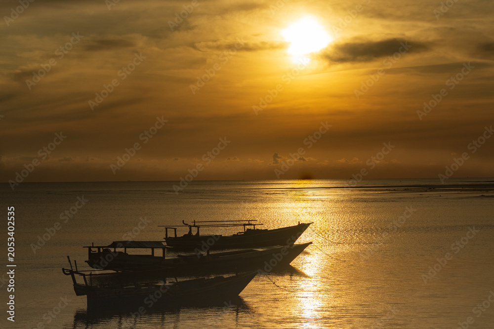 Obraz premium It's still early morning, the sun has just risen higher, a golden yellow color appears, no fishermen have gone out to sea yet, and a few wooden boats are still seen moored near the dock