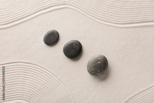 Photography Zen garden with three smooth black stones on raked sand, serenity and balance fo