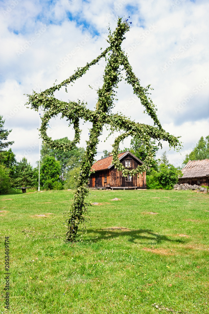 Obraz premium Maypole on a lawn by old wooden croft a sunny summer day