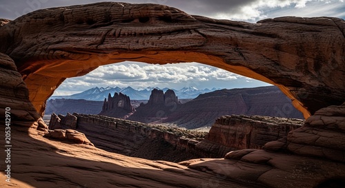 Sandstone arch overlooking desert canyon and snowcapped mountains