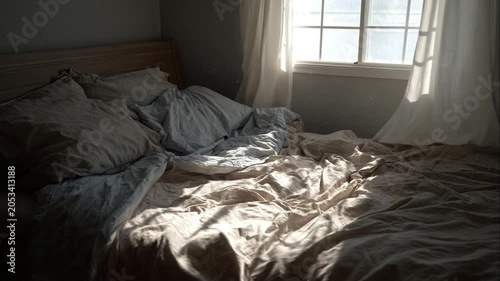 Sunlight streaming into a messy bedroom, morning light on unmade bed, cozy atmosphere