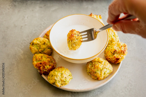 Foto Close-up of a golden crispy baked zucchini tot being dipped into a small bowl of