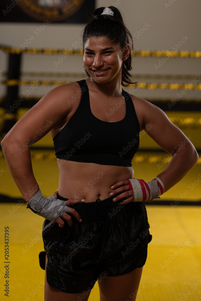 Naklejka premium Confident Female Boxer Athlete Smiling in Boxing Gym After Training Session With Hand Wraps