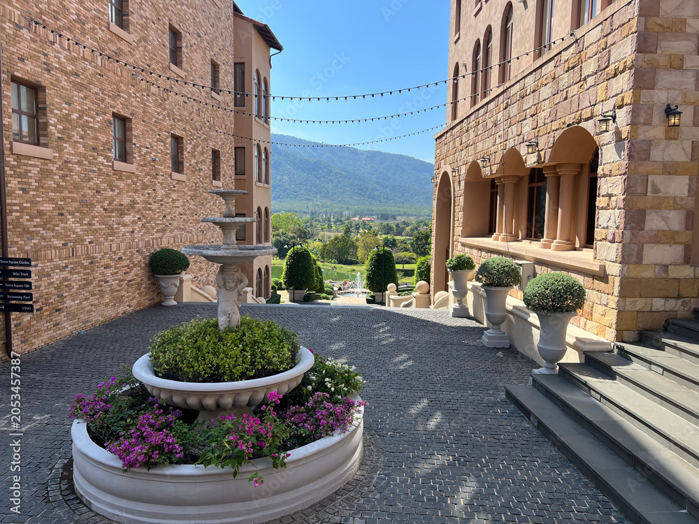 Naklejka premium Mediterranean Style Courtyard with Stone Fountain and Mountain View