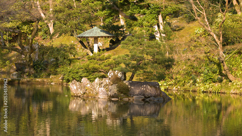 Foto Serene Japanese Garden Pond with Stone Lantern and Pine Tree Reflections
