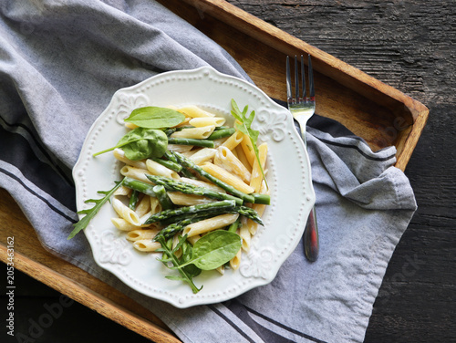 Penne pasta with asparagus and cream sauce on a wooden tray