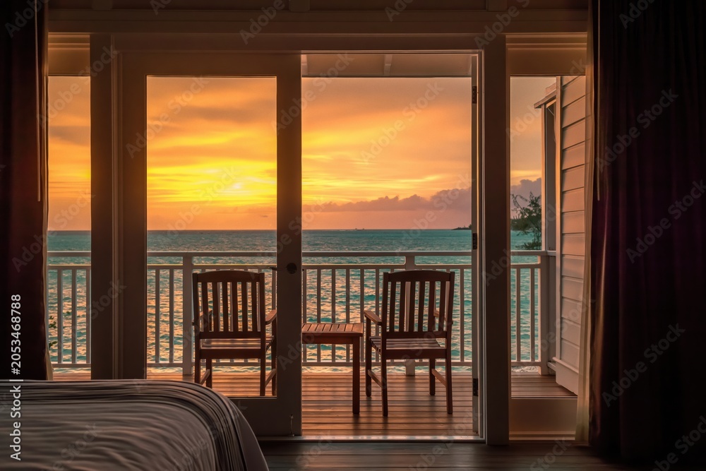 Fototapeta premium Sunset view from hotel room balcony overlooking ocean at tropical resort vacation