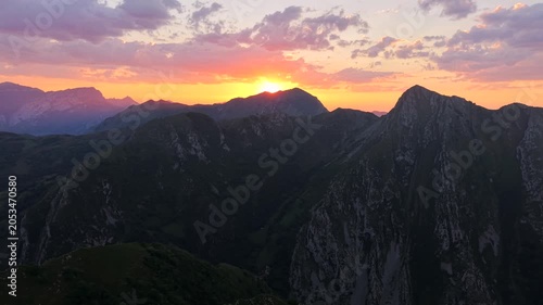 Drone shot moving left to right with aerial view above rocky mountain tops in Europe at sunset. Footage filmed in Pico de Europa mountains of northern, Spain with beautiful evening sky.