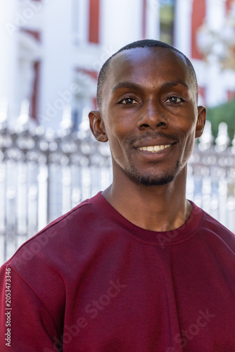 Photos African American man standing, smiling in maroon crewneck before ornate fence an