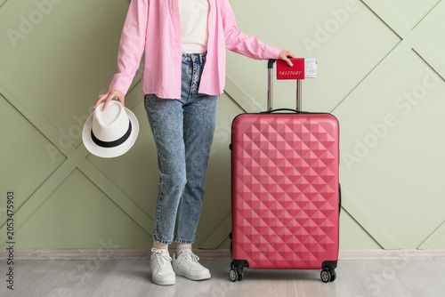 Young woman holding passport and boarding pass with pink suitcase, ready for international travel and vacation