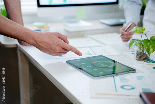 Fotografie Business professionals analyzing financial data and ESG metrics on a tablet, pla