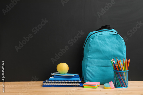 Bild auf Leinwand Back to school education with blue backpack, stack of notebooks, apple, and penc