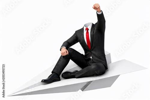 Headless businessman sitting on paper airplane with success gesture