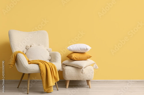 Bild auf Leinwand Cozy living room interior with cream armchair, yellow blanket, and decorative pi