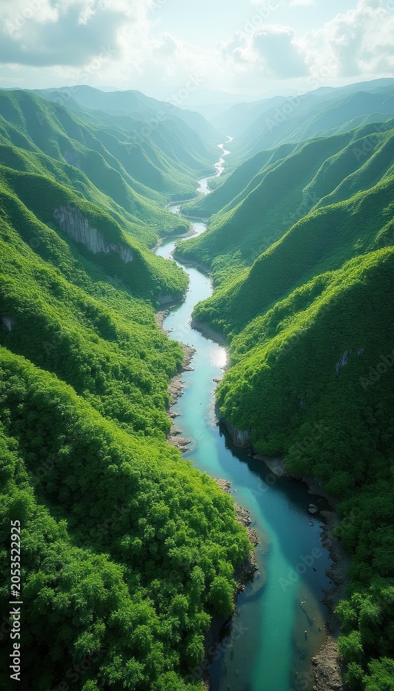 Naklejka premium Aerial view of winding turquoise river flowing through rich green mountain valley. Steep hills covered with dense trees rise on both sides. Bright sunlight illuminates clouds, water surface, creating