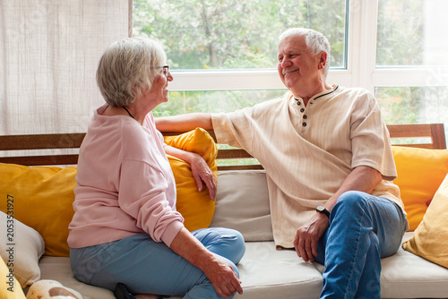 Senior woman and senior man sitting on couch and talking. Elderly couple communicating at home. Happy retired husband and wife resting together. Relationship  love and lifestyle concept.