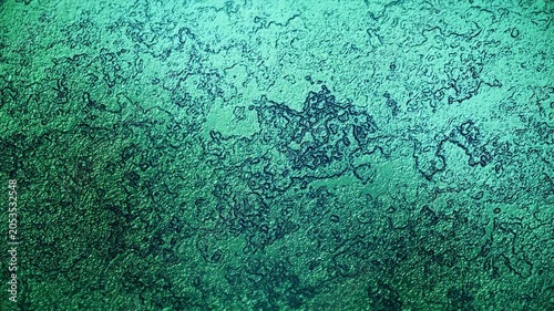 Slowly moving emerald green metallic fluid with a rough organic texture and glossy reflections for background video.