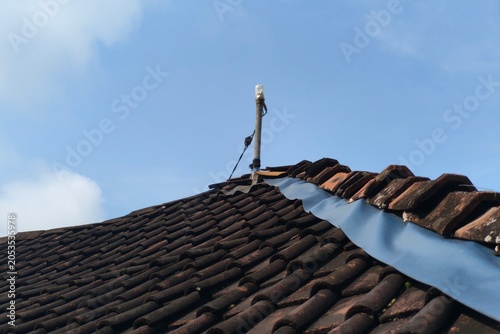 Photos A DIY improvised antenna mounted on a pole atop a rustic tiled roof, housed in a