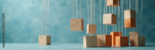 Wooden cubes hang on strings forming abstract 3D structure. Objects float in air against textured blue background. Shapes connect  create balance  represent stability or instability.