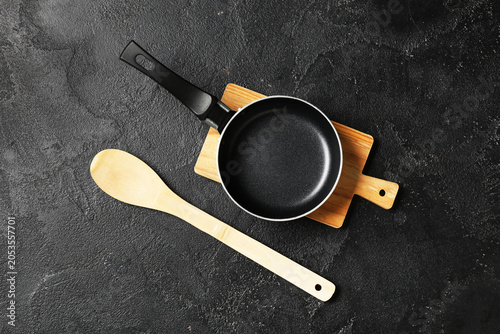 Φωτογραφία Empty frying pan and wooden spoon on cutting board, kitchen utensils for cooking