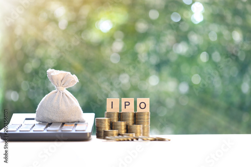 фотографія Money bag on a calculator with wooden blocks spelling IPO on coin stacks, symbol