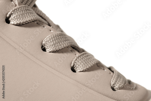Close-up of beige sneaker showing laces and eyelets
