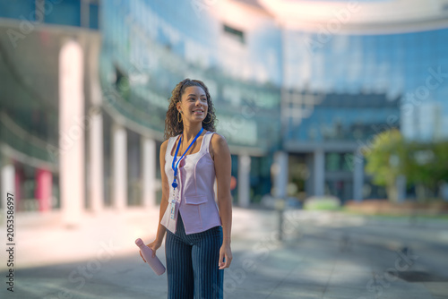Confident businesswoman walking outside in a contemporary corporate environment holding a reusable bottle