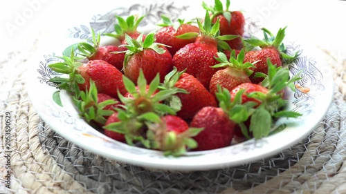 strawberries, skillfully arranged on a decorative vintage porcelain plate, highlight their vibrant red color and lush green leaves. Perfect for showcasing natural beauty in cooking or as part of a hea