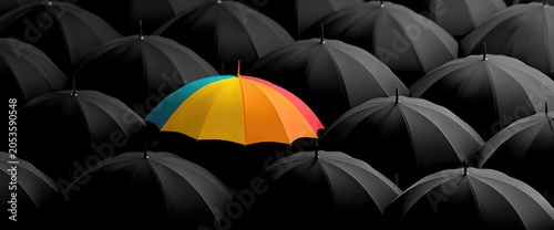 A vibrant, colorful umbrella stands out amidst a sea of closed black umbrellas, conveying contrast and uniqueness
