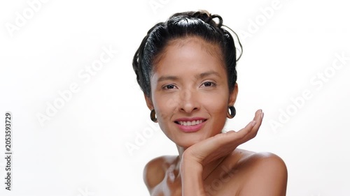Close-up shot of smiling south american woman with warm toned skin rests chin on palm demonstrating firm skin on studio white background | Face care commercial
