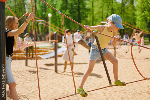 Bild auf Leinwand Girl having fun on a rope climbing frame at a playground on a sunny day