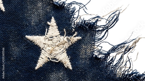 Torn denim fabric with white star, frayed edges, blue jeans texture, close-up