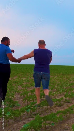 An emotional embrace of two handsome mature men walking in nature. A happy gay couple on a walk in a field, having a fun time. Vertical video.