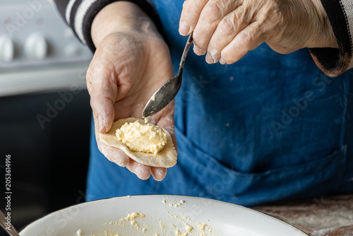 Fotografija Elderly person hands filling dough with curd to prepare traditional dumplings, e