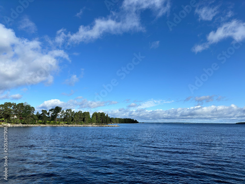 Tableau sur toile Serene Swedish lake landscape with blue sky and fluffy clouds over calm water