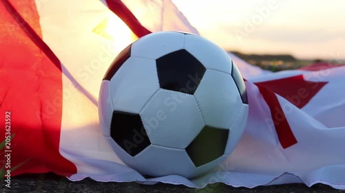 Black and white soccer ball placed on a Canadian flag outdoors, illuminated by golden sunset light. This symbolizes the excitement for the 2026 World Cup hosted by Canada and USA