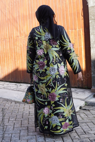Canvas Print Full back view of a Muslim woman in a black hijab and an elegant floral embroidered long gown