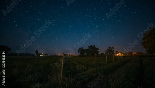 Starry Night Over Rural Countryside Landscape with Illuminated Horizon