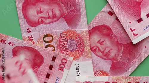 Chinese 100 yuan banknote (CNY) or renminbi (RMB) falling on green table surface. Closeup real time footage.