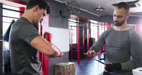 Picking wraps indian instructor guiding trainee wrapping red and black wraps in boxing area