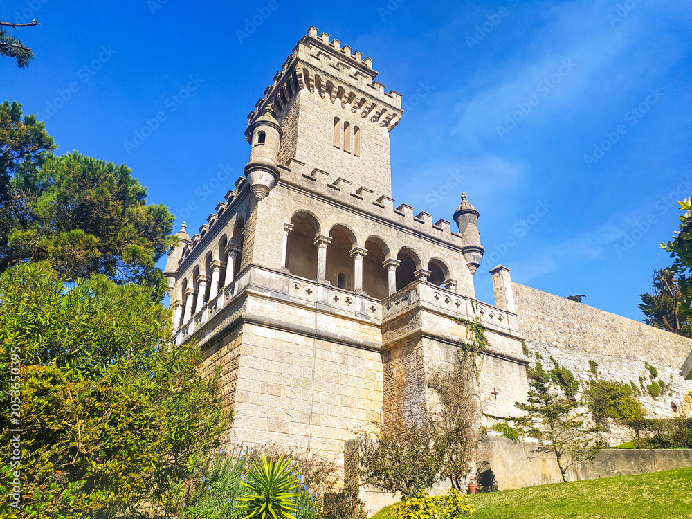 Fototapeta premium Majestic stone castle tower with elegant arches under a clear blue sky. A symbol of strength and historic European architecture, perfect for travel, heritage, or luxury lifestyle themes.