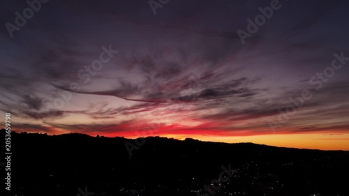 Dramatic sunset sky over hills and city lights at dusk